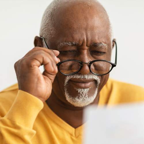 Middle aged gentleman using his reading glasses to read a paper