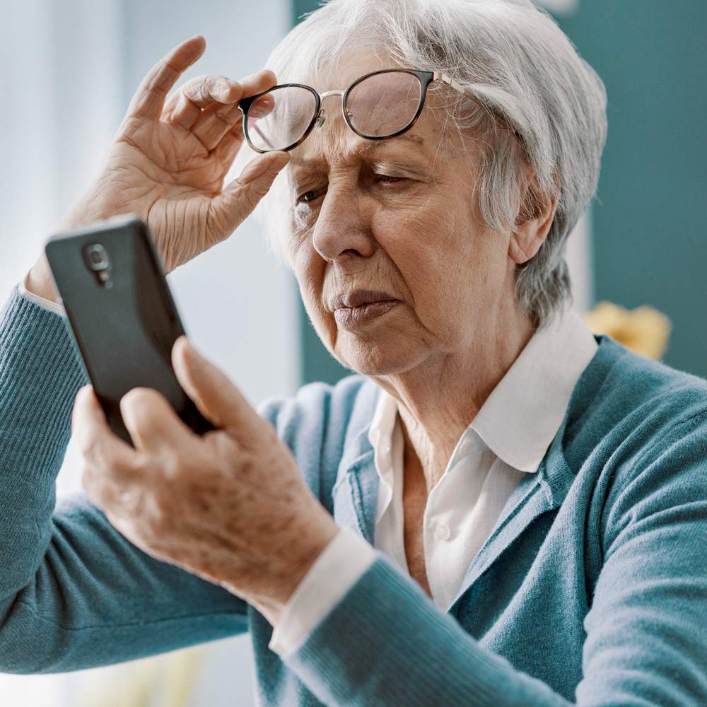 Elderly woman struggling to read her phone